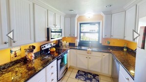 A kitchen with white cabinets, a granite countertop, and a window with a view.