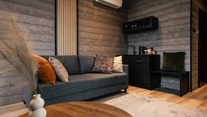 Ein modernes Wohnzimmer mit grauem Sofa, Holzboden und einem schwarzen Schrank.