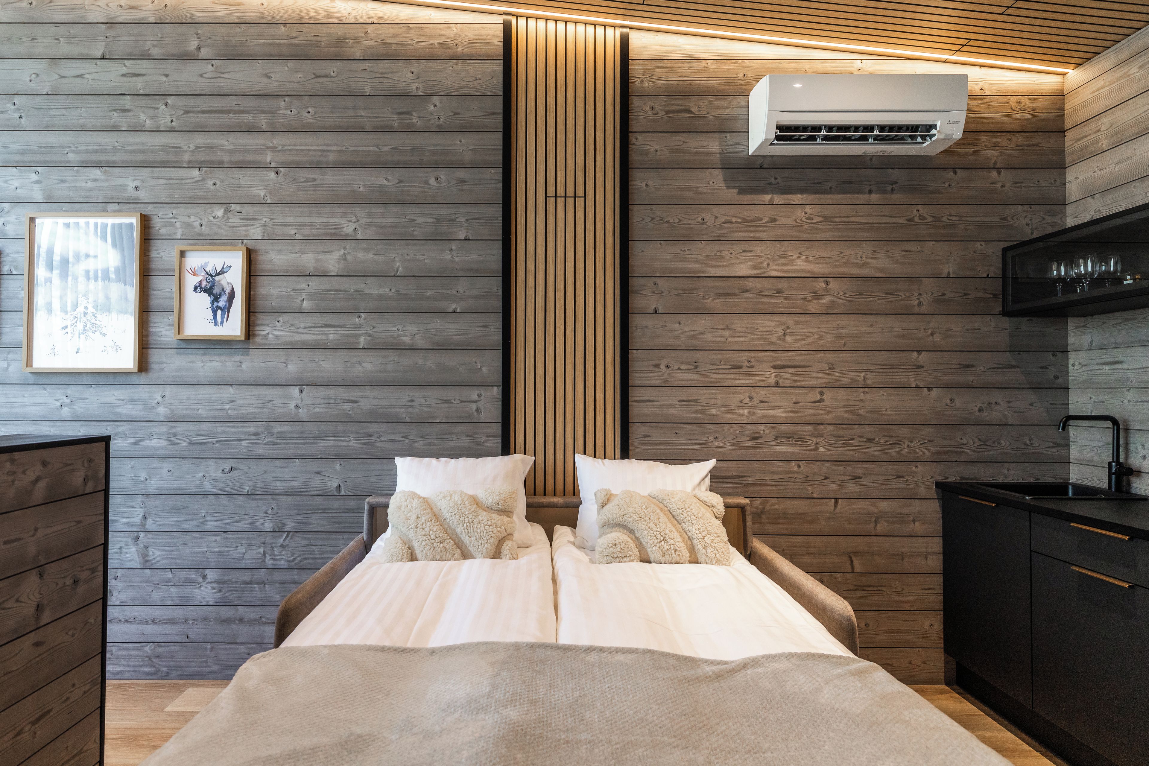 Une chambre comprenant un lit, une commode, un appareil de climatisation et un tableau encadré accroché au mur.