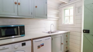 Cozinha compacta com máquina de lavar, micro-ondas e pia.