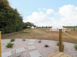 Un terrain de camping avec des tentes, des tables de pique-nique et une clôture en bois.
