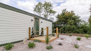 Een laag gebouw met houten terras en een grindpad dat naar de ingang leidt.