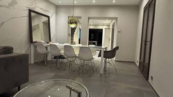 Un espace de salle à manger moderne avec un mur en marbre, un grand miroir, une table en verre et des chaises contemporaines.