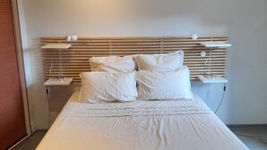 A neatly made bed with white linens and pillows, a wooden slatted headboard, and a bedside table with a lamp. - Top Location: Panoramic Villa with Pool Monaco Bay (Roquebrune Cap Martin)