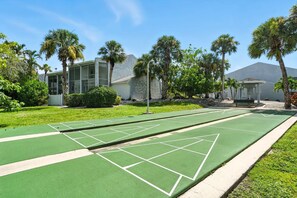 Un terrain de jeu de shuffleboard vert, avec un bâtiment en arrière-plan.