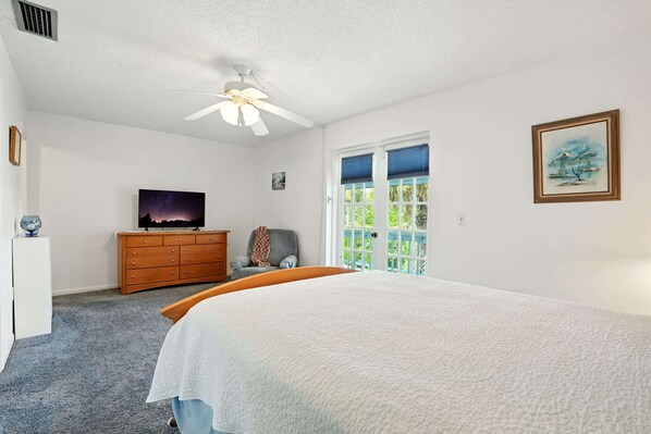 A bedroom with a large bed, a ceiling fan, a dresser, a television, and a window with blinds. - Naples Retreat - Walk to Pool and More (Naples)