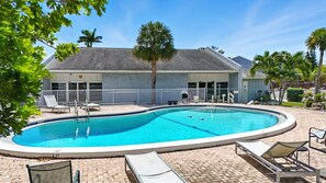 A swimming pool with lounge chairs and a fenced deck area.