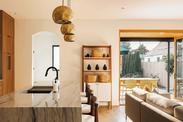 A modern kitchen with a marble countertop, a built-in sink, and a pendant light.