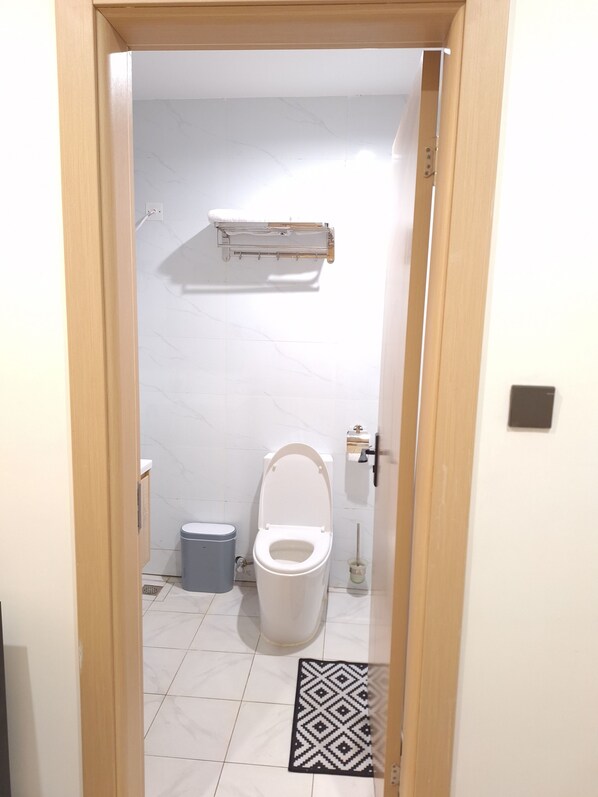 Un baño pequeño con inodoro, un bote de basura y zona de ducha.