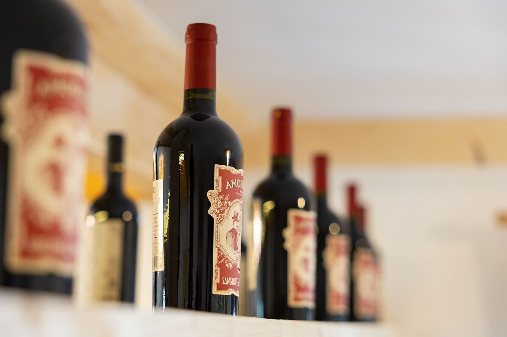 Una hilera de botellas de vino con etiquetas, probablemente en una sala de degustación o bodega.
