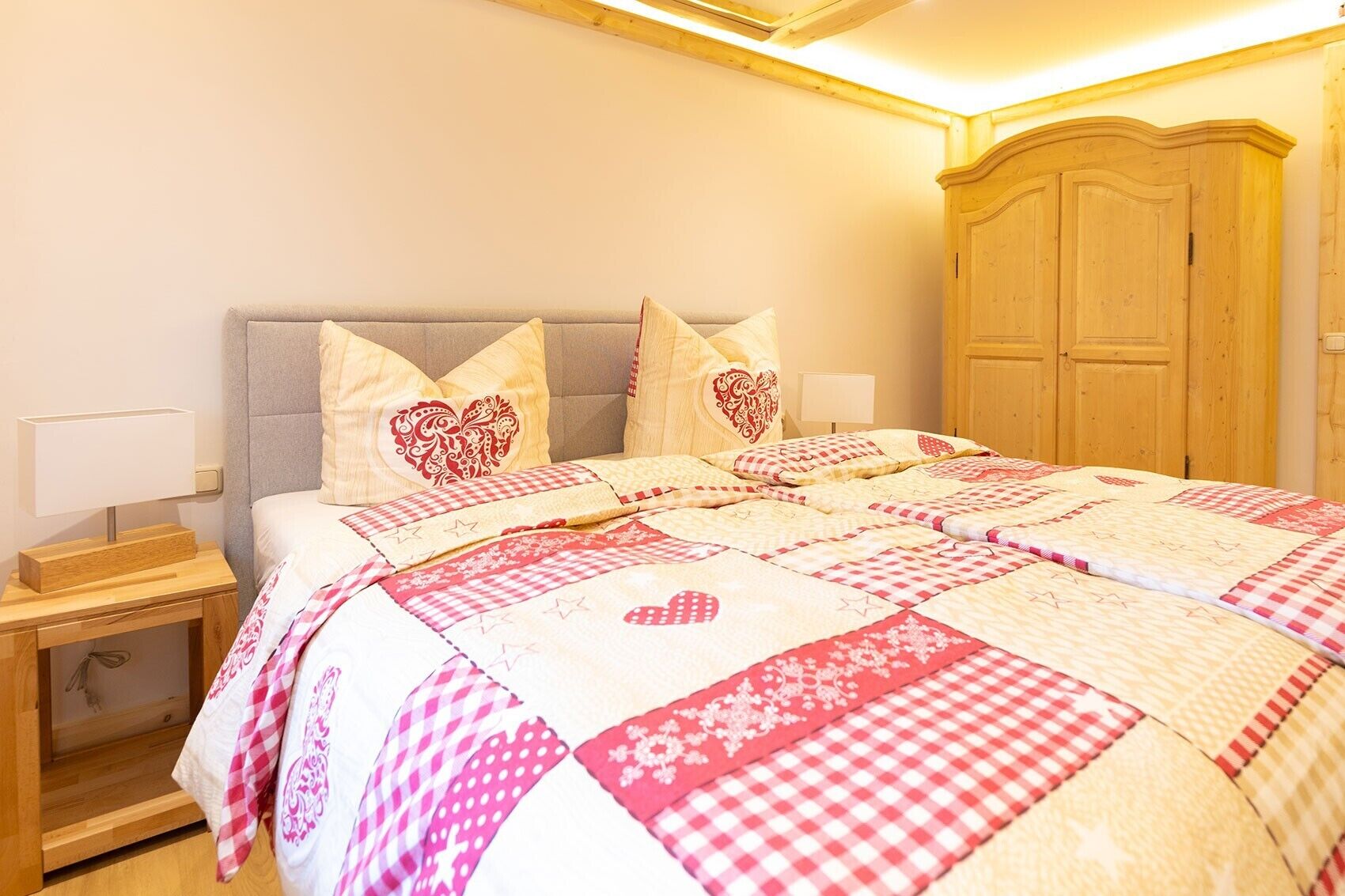 Ein Schlafzimmer mit einem Bett, Kissen, einem Nachttisch, einem Holzschrank und einer Deckenleuchte.