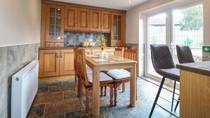 Una cocina con armarios de madera, una mesa de comedor con sillas y vista al exterior por un gran ventanal.