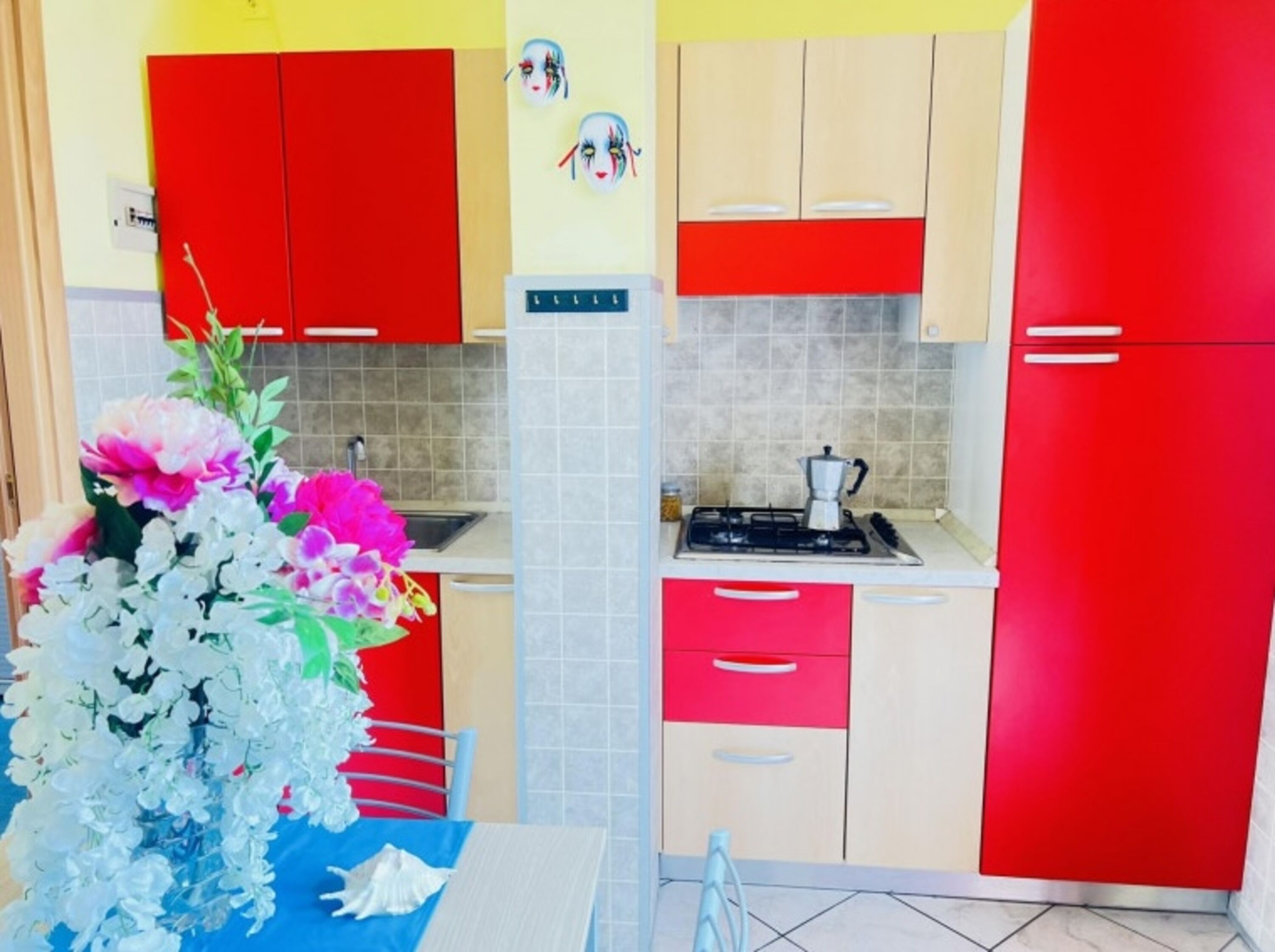 A kitchen with red and beige cabinets, a gas stove, and a sink.