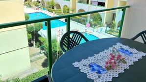 A balcony with a view of a swimming pool and adjacent buildings.
