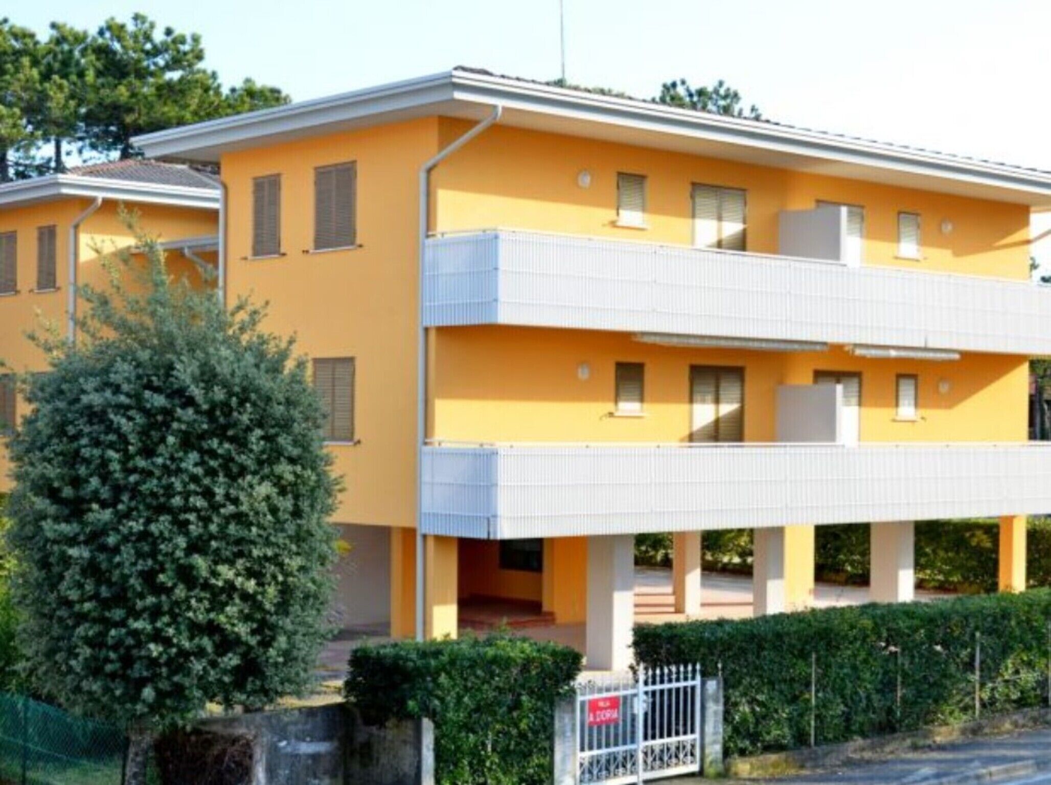 A yellow building with a balcony, a fenced area, and a sign that reads "A SPA".