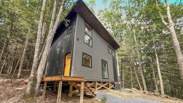 A cabin with a wooden deck, built on stilts, surrounded by a forest. - Coal Ridge Cabin - WV Retreat with Family History (Summersville)