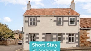 Un edificio de dos plantas con techo de tejas y un letrero que indica 'Short Stay St Andrews'.