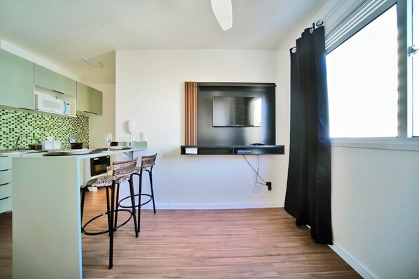 A modern kitchen with a microwave, a coffee machine, and a small dining area with two chairs.