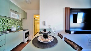 A modern kitchen with a dining area, a microwave, a stove, and a TV mounted on the wall. - Apartamento no centro de SP - 1209A (São Paulo)