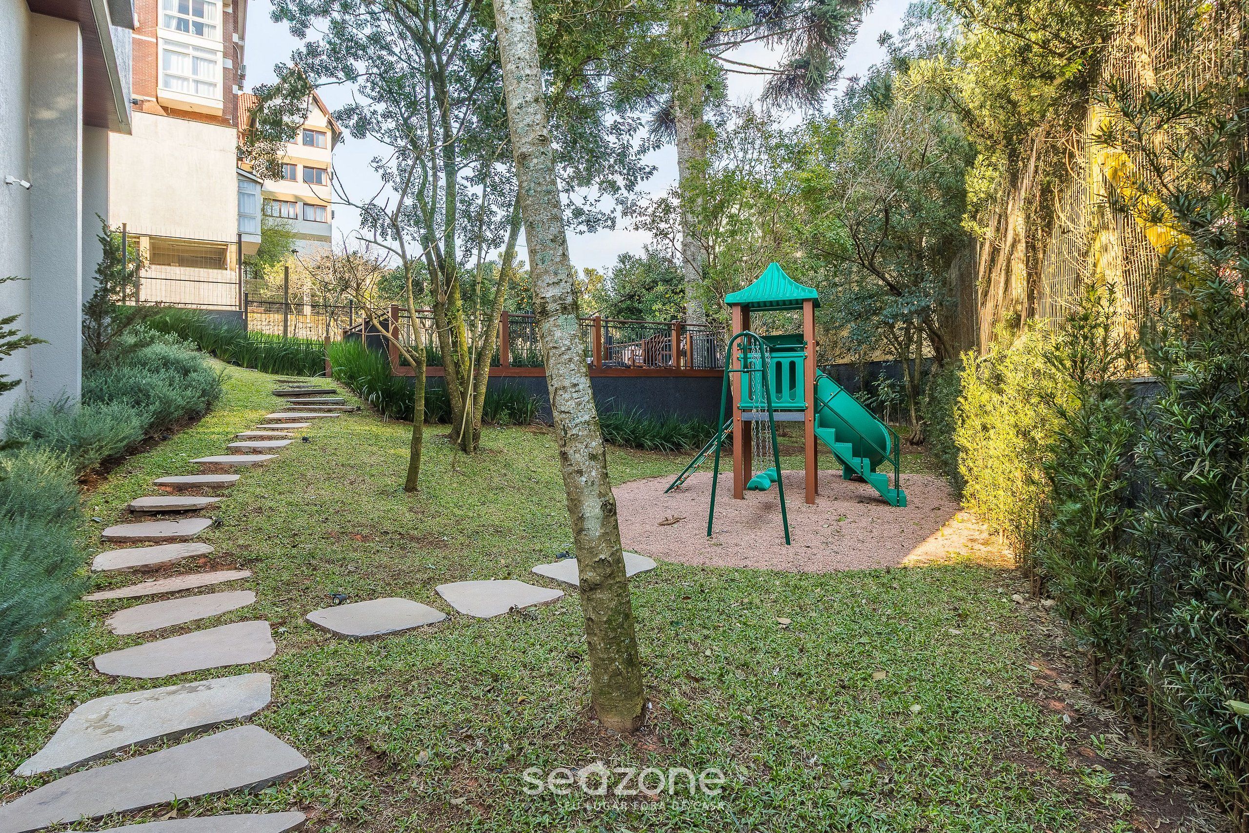 Ein Spielplatz mit Rutsche und Klettergerüsten, umgeben von einem Garten mit einem Kiesweg.