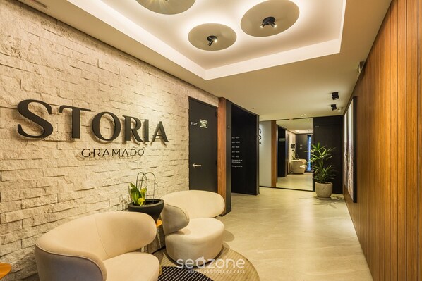 A modern hotel lobby with a stone wall, a reception desk, and seating area.