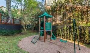 A playground with a climbing structure, slides, and swings. - Charming apartment with fireplace in Gramado STA0305 (Gramado)