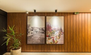 Two framed pictures on a wooden wall, a potted plant, and a directional sign. - Charming apartment with fireplace in Gramado STA0305 (Gramado)