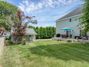 A backyard with a covered patio, a grill, and outdoor furniture.