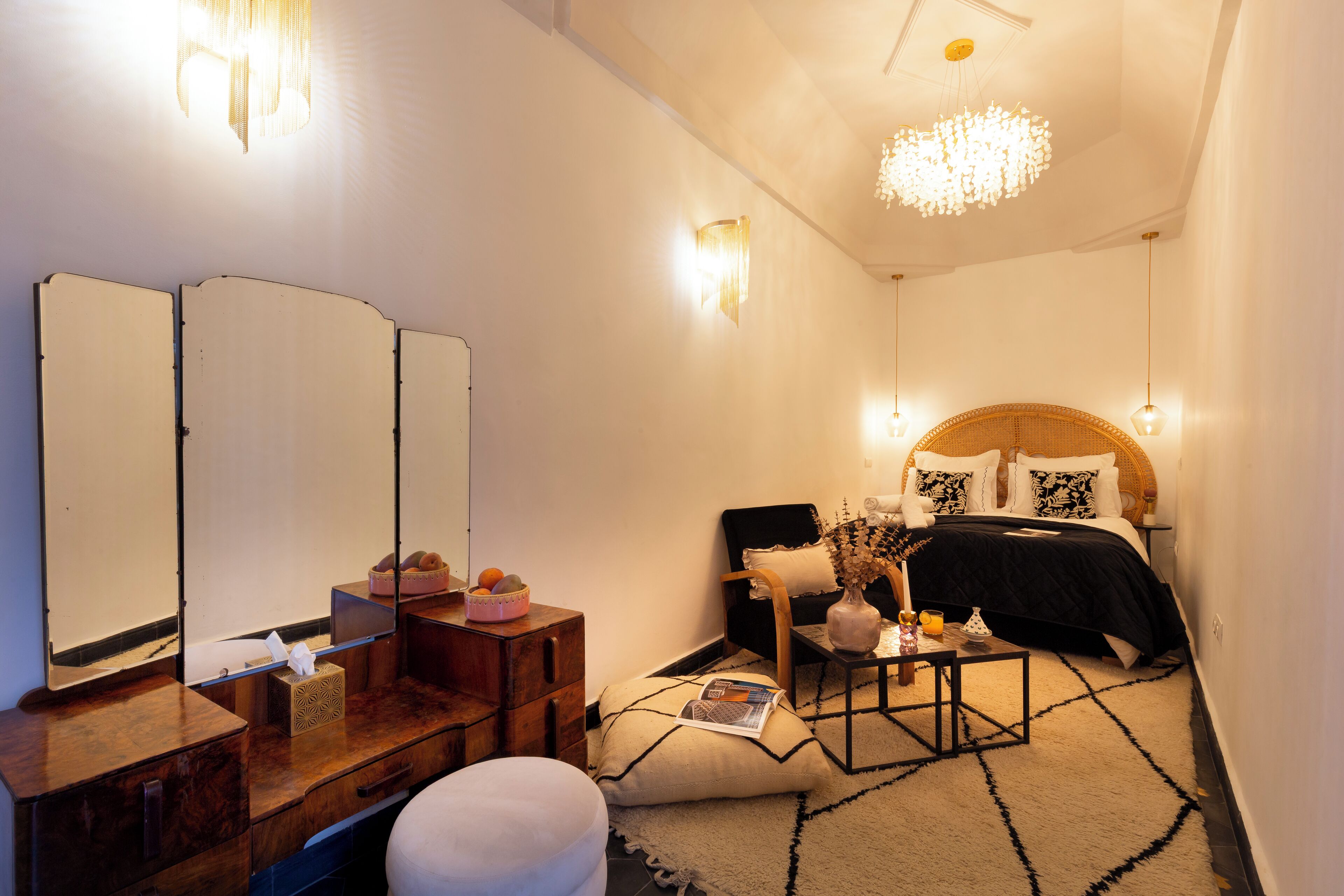 A compact bedroom with a bed, bedside tables, a dresser, a mirror, and a chandelier.
