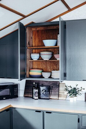 A kitchen with a wooden cabinet shelf holding various bowls and a microwave. - Newly Renovated Lake Cottage, 10 Mins From Bancroft, Beautiful Sandy Beach! (FARA)