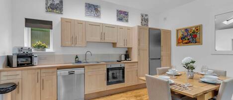 A modern kitchen with wooden cabinets, a dishwasher, and a dining area with a table set for four.