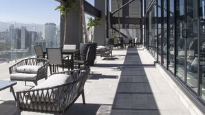 Une terrasse sur le toit avec des espaces de détente en plein air, des palmiers et une vue sur la ville.