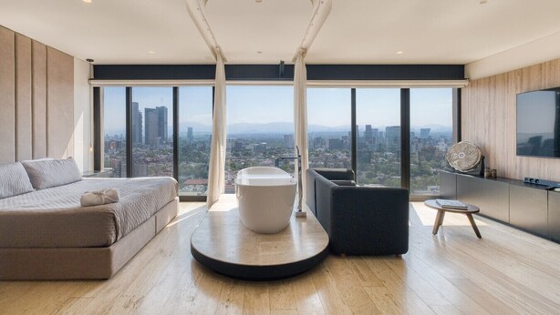 Un salon moderne avec une grande fenêtre, une table basse ronde, un canapé et un téléviseur.