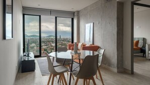 Een moderne eethoek met een ronde tafel, stoelen en een stadszicht door grote ramen.