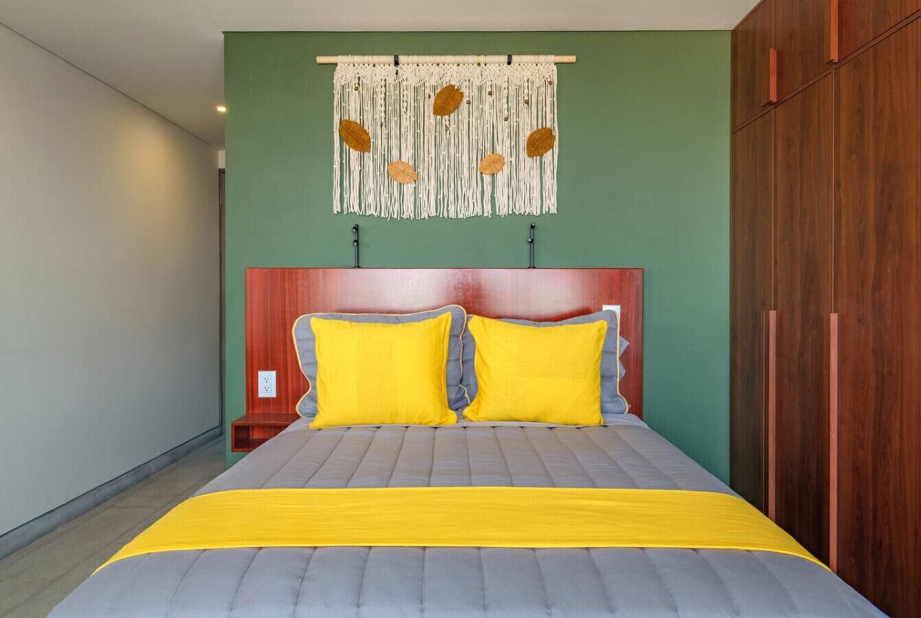 A bed with a wooden headboard, two yellow pillows, and a yellow bedspread.