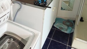 A laundry area with a washing machine, a drying rack, and a box of detergent on the counter. - No luxury accommodation For two people (Concarneau)