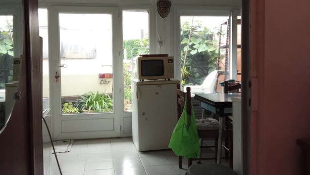 A room with a tiled floor, a microwave, a trash bin, and a green bag. - No luxury accommodation For two people (Concarneau)