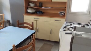 A compact kitchen with a dining table, chairs, a stove, and cabinets. - No luxury accommodation For two people (Concarneau)