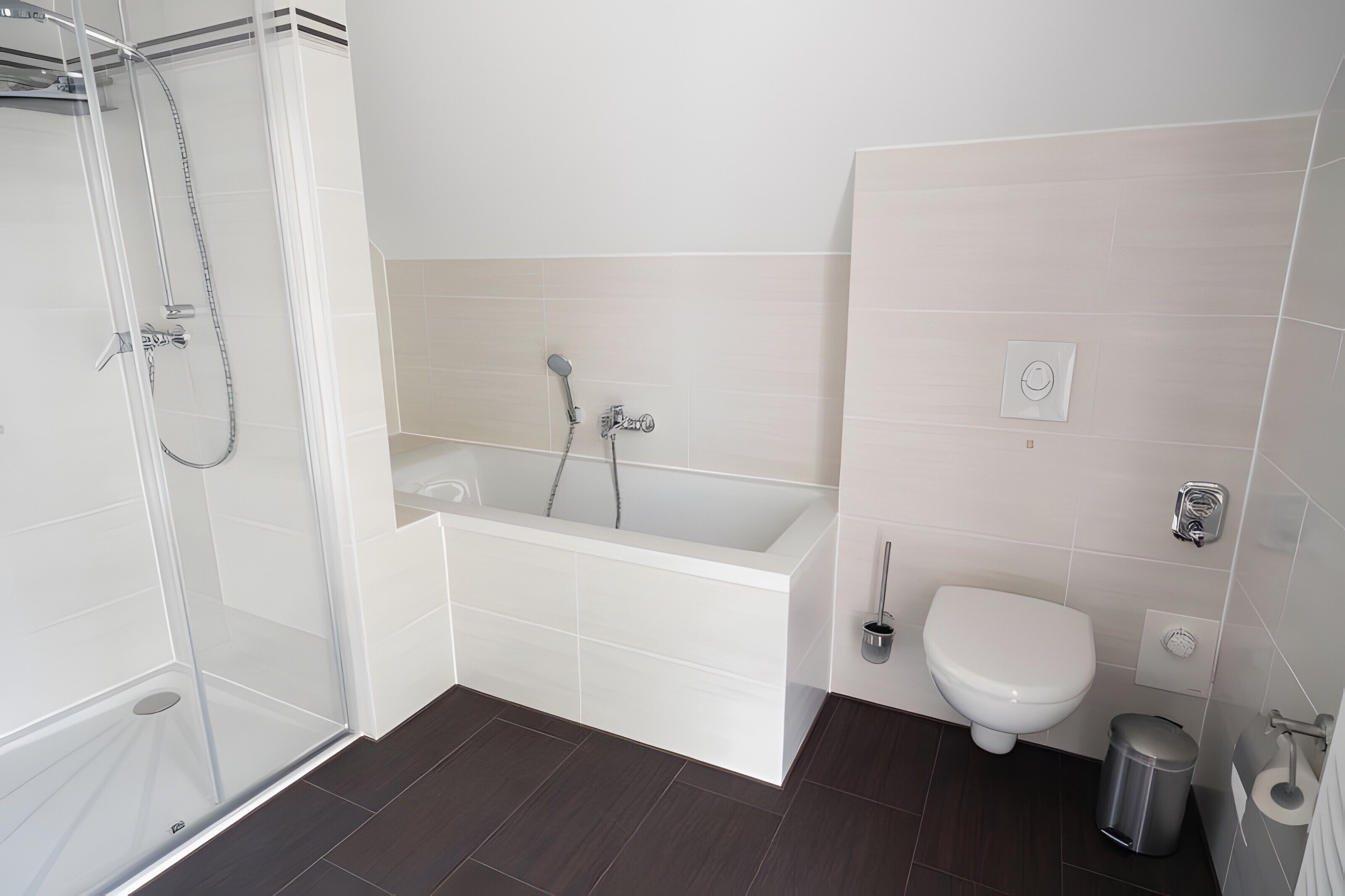 A modern bathroom with a glass shower enclosure, a bathtub, a toilet, and a trash bin.