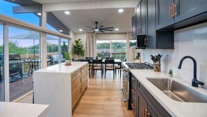 A modern kitchen with dark cabinets, a large island, and a view of the outdoors.