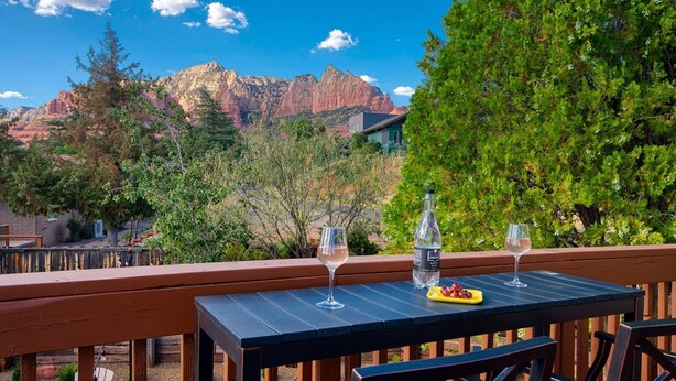 An outdoor dining area with a table set for two, overlooking a mountainous landscape.