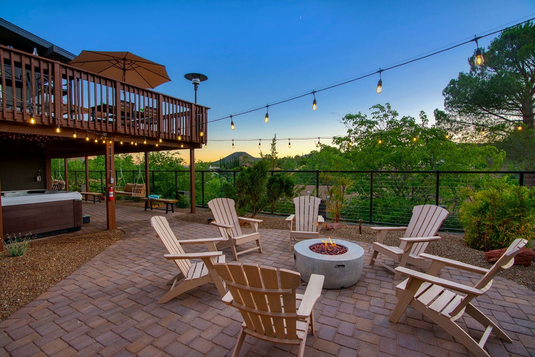 Une terrasse extérieure avec des fauteuils Adirondack, un foyer et des guirlandes lumineuses.