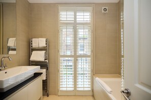 A bathroom with a sink, towel rack, and a shower.