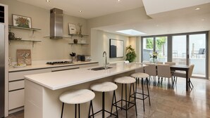 Cozinha moderna com ilha central, banquetas e área de refeições com uma janela grande.