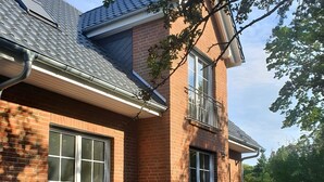 A brick house with large windows, a covered patio, and outdoor seating. - Apartment 1, ground floor, 85 sqm, 2 bedrooms, for up to 4 people (Potsdam)