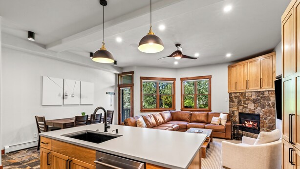 A modern kitchen with a central island, wooden cabinets, and pendant lighting.