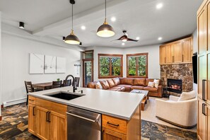 A modern kitchen with a central island, wooden cabinets, and pendant lighting. - Stylish, Inviting Townhome~Near Skiing~Hot Tub+Pool (Steamboat Springs)