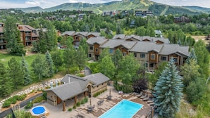A resort with multiple buildings, a swimming pool, and a mountain backdrop.