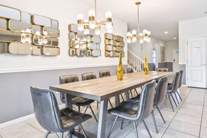 A modern dining area with a long wooden table, black leather chairs, and a decorative gold vase.