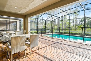Une terrasse extérieure avec des meubles en osier et une piscine.